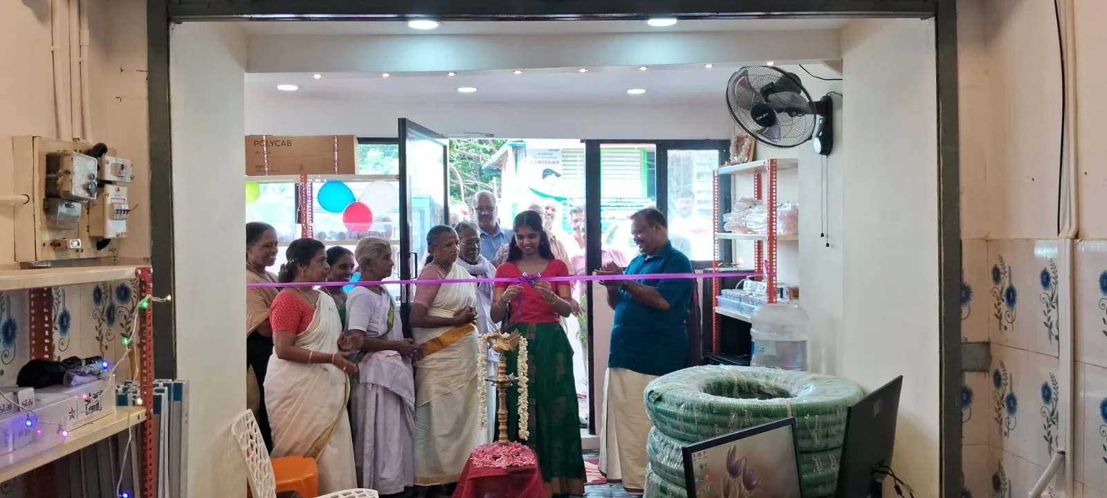 Guests cutting the ribbon at the opening of RRR Traders, with proprietor Rajan C in a blue shirt on the right